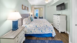 A bedroom with a bed, a dresser, a television, and a ceiling fan.