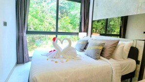 A bed with a white bedspread, two swan-shaped pillows, and a heart-shaped decoration made of flowers. - A307- 2 Bedroom Serviced Apartment with Forest View at Ao Nang Beach (Tambon Ao Nang)