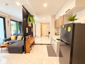 A modern kitchen with a black refrigerator, wooden cabinets, and a marble floor.