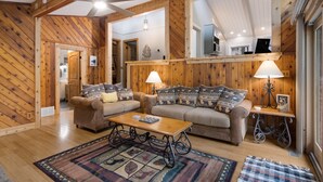 A cozy living room with wooden walls, two sofas, a coffee table, and a ceiling fan. - Torch Lake cabin, 4BR, Sleeps 10, Firepit, A/C (Rapid City)