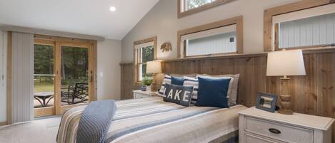 A bedroom with a large bed, wooden headboard, and a view of a patio.