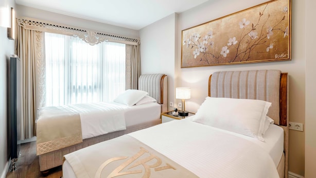 A hotel room with two beds, a painting, a nightstand, and a radiator. - Bellavia Deluxe Apart (Istanbul)