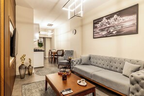 Ein modernes Wohnzimmer mit einem grauen Sofa, einem Holztisch und einem Gemälde an der Wand.