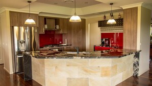 Cozinha moderna com ilha central, eletrodomésticos de aço inoxidável e iluminação pendente.