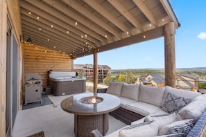 An outdoor patio with a fire pit, seating area, and a hot tub.