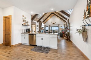 A spacious kitchen with white cabinets, a stainless steel dishwasher, and a wooden ceiling.