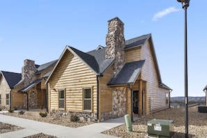 A log cabin with a stone chimney, a stone foundation, and a clear sky. - Ozark Sunset View Log Cabin with $400 Daily Activities Included & Pickleball (Branson)