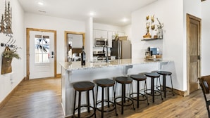 A modern kitchen with a central island, bar stools, and a wooden floor. - Ozark Sunset View Log Cabin with $400 Daily Activities Included & Pickleball (Branson)