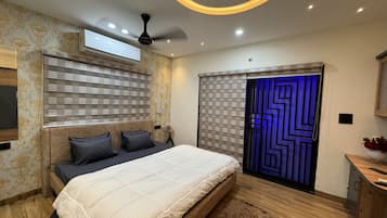 A bedroom with a bed, a ceiling fan, a window with blinds, a wall-mounted air conditioner, and a decorative wall panel.