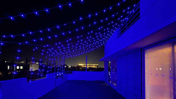 Eine Dachterrasse mit Lichterketten und Blick auf die Stadt.
