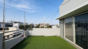 Eine Dachterrasse mit Kunstgrasanlage, einer weißen Wand und einem modernen Gebäude mit großen Fenstern.