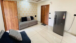 Ein Zimmer mit einer Couch, einem Kühlschrank und zwei Holztüren.