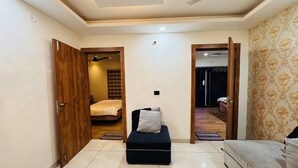 Ein geräumiger Wohnbereich mit Sofa, Hocker und einem Bett im Hintergrund.