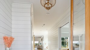 A hallway with wooden floors, white walls, and a patterned cabinet.