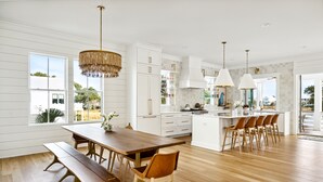 A spacious kitchen with white cabinetry, a wooden dining table, and a central island with bar stools.