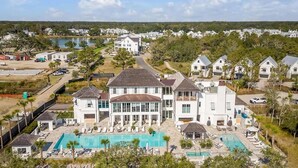 A large white building with a swimming pool and multiple guest rooms.