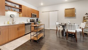 Une cuisine moderne avec des meubles en bois, un four à micro-ondes et un coin repas doté de chaises à rayures.