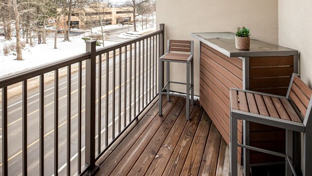 Une terrasse en bois avec une rambarde, un banc et une petite table agrémentée d’une plante.