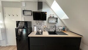 Una cucina compatta con frigorifero nero, forno a microonde, lavandino e un piccolo piano di lavoro.