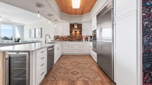 A modern kitchen with white cabinets, a built-in oven, and a patterned rug. - Family-Friendly Two Bedroom Unit with Phenomenal Gulf and Bay Views. Complimentary Boat Slip! (Orange Beach)