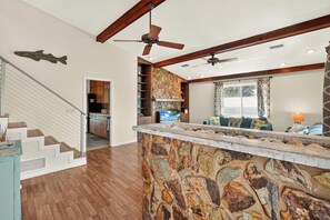 A spacious living area with a stone accent wall, a kitchen with wooden cabinets, a dining area with a view, and a staircase.