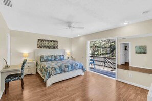 A bedroom with a bed, a desk, a chair, a ceiling fan, and a large mirror. - Nokomis Beach Getaway with Heated Pool (Nokomis)