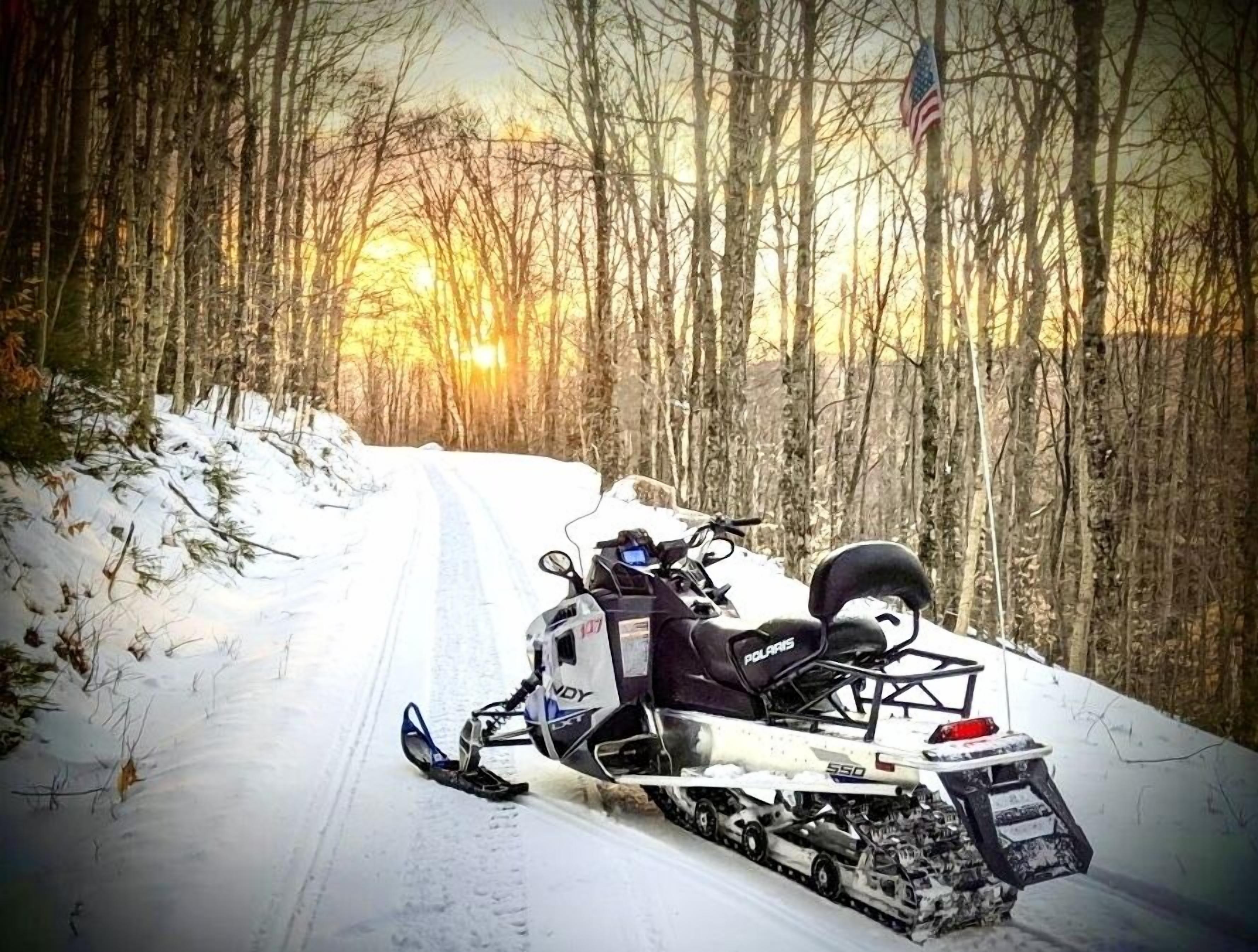 Una moto de nieve estacionada en un camino nevado en un bosque.