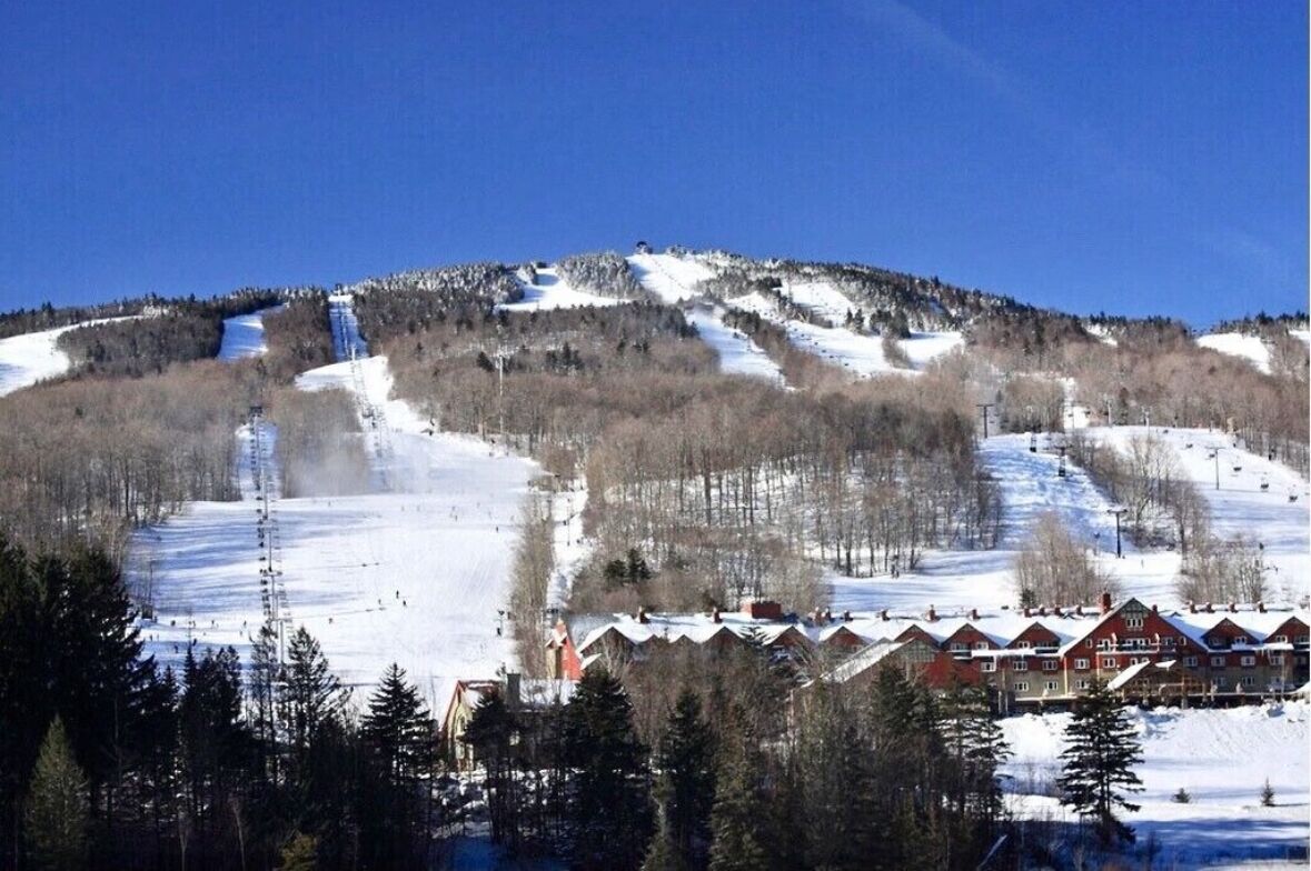 Une station de ski avec une vue sur les montagnes, des remontées mécaniques et des bâtiments d’hébergement.