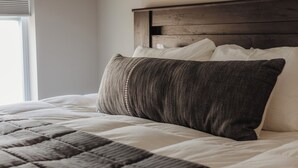 A neatly made bed with a quilted headboard and a window with blinds. - Heated Private Pool, Spacious, Hot Tub All Year (New Buffalo)