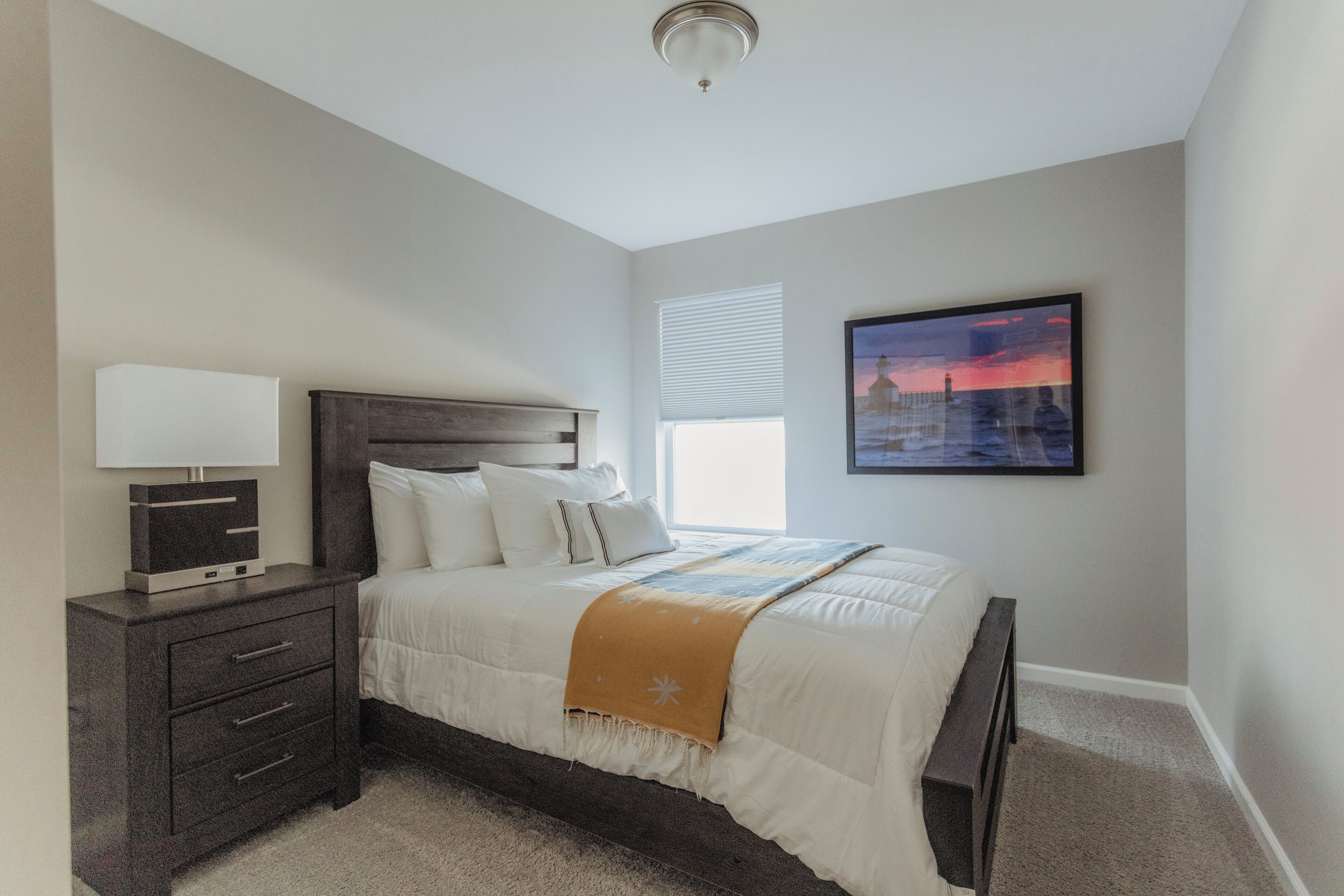A bedroom with a bed, bedside table, and a window with blinds.