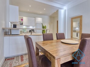 Enjoy meals in this kitchen with a dining table and six chairs, a large mirror, and a patterned rug.