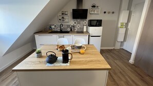 A modern kitchen with a wooden countertop, white cabinets, and a black and white patterned backsplash. - Studio Scandinave - Duplex - Hyper Centre (Lorient)