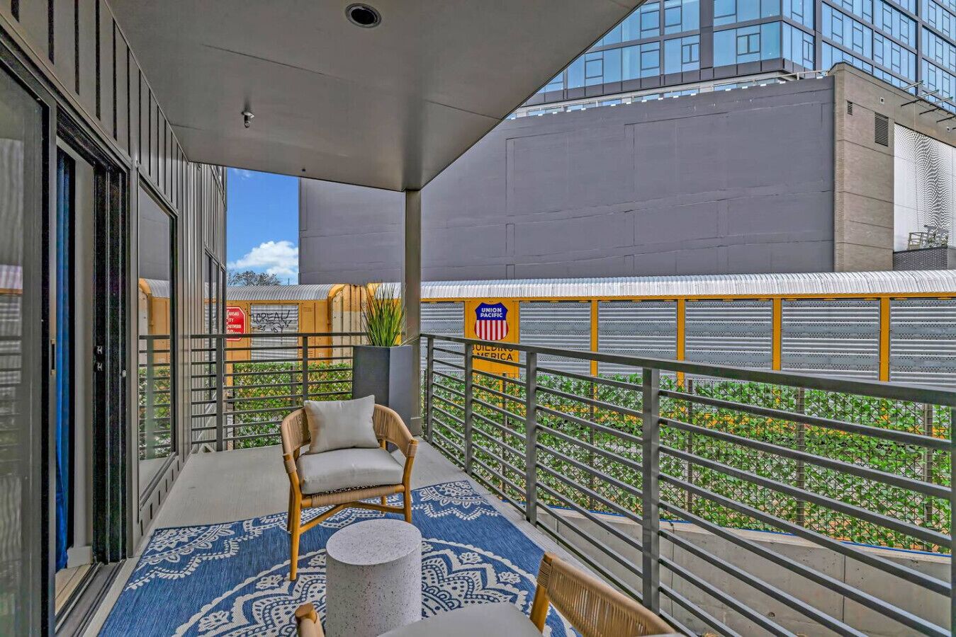 Un balcon avec une chaise, une petite table et un tapis à motifs.