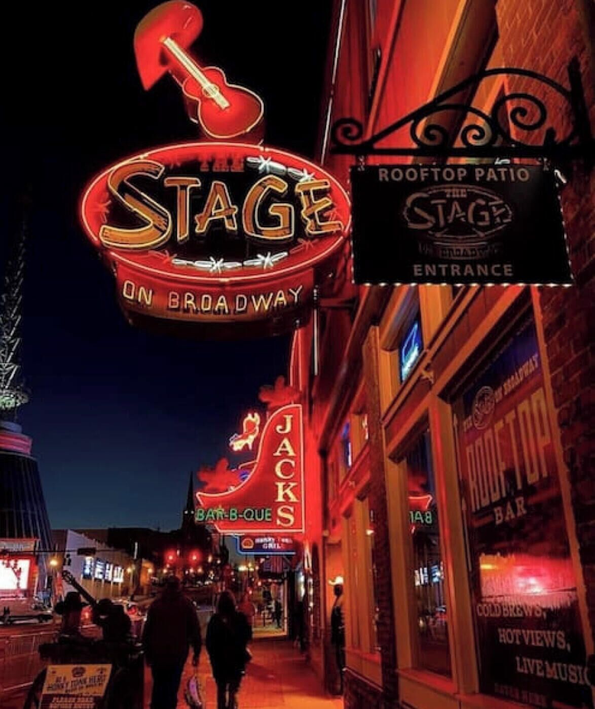Une enseigne au néon indiquant « Stage on Broadway », avec les mentions « Rooftop Patio » et « Entrée » en dessous.