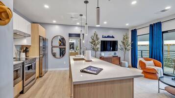 A modern kitchen with a central island, built-in oven, and a dining area with a view.