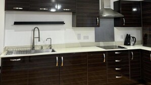 A modern kitchen with dark wood cabinets, a stainless steel sink, and a built-in oven. - Stunning 2-bed Apartment in Dartford (Dartford)