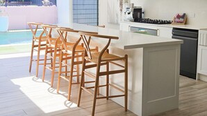 Una cocina moderna con armarios blancos, una estufa a gas y una zona de bar con taburetes de madera.