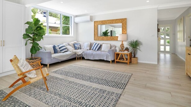 Una sala de estar moderna con un sofá seccional, un sillón de ratán y un tapete estampado.