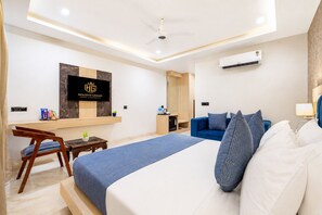A modern hotel room with a bed, a desk, a TV, and an air conditioning unit.