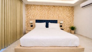 A modern bedroom with a large bed, wooden headboard, bedside lamps, and a potted plant. - Hotel Holiday Grand Near Expo Mart (Greater Noida)