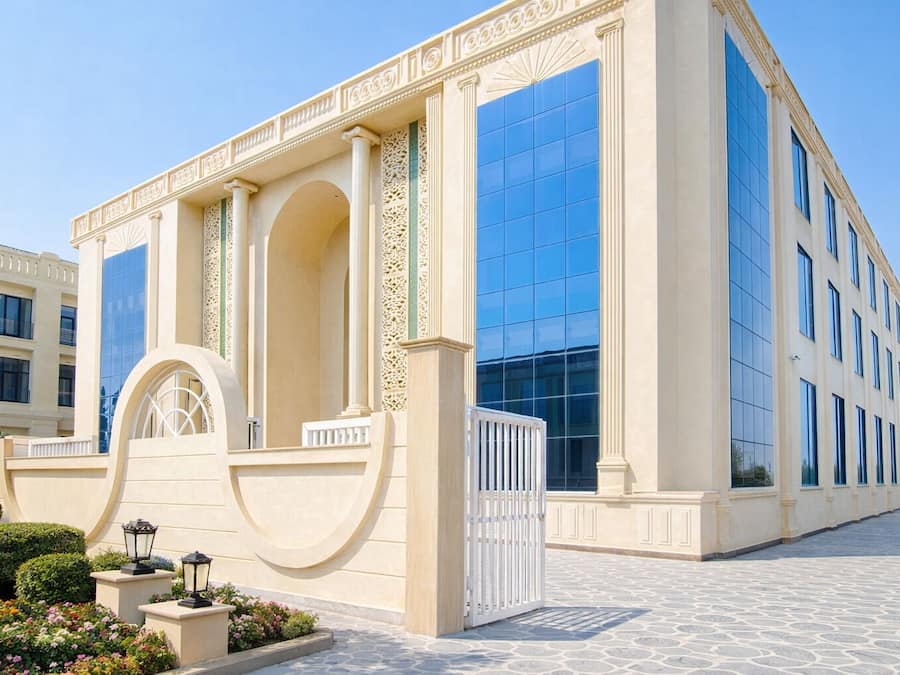 Un edificio moderno con ventanas amplias, un arco central y una entrada protegida por una reja.