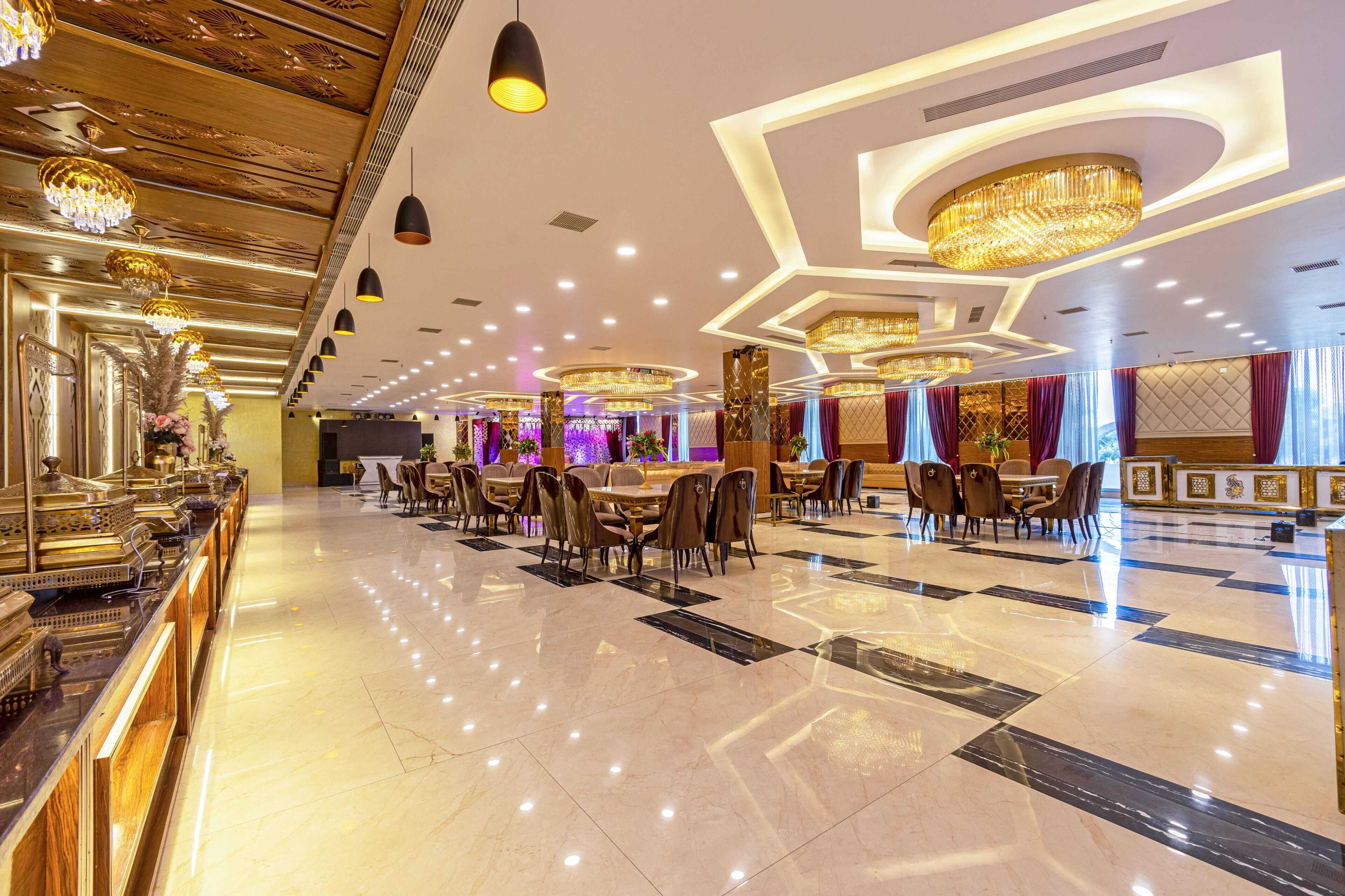 A spacious hotel lobby with a polished marble floor, elegant chandeliers, and a long reception desk.