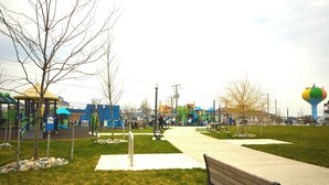 Un parque con un parque infantil, bancos y una torre de agua.
