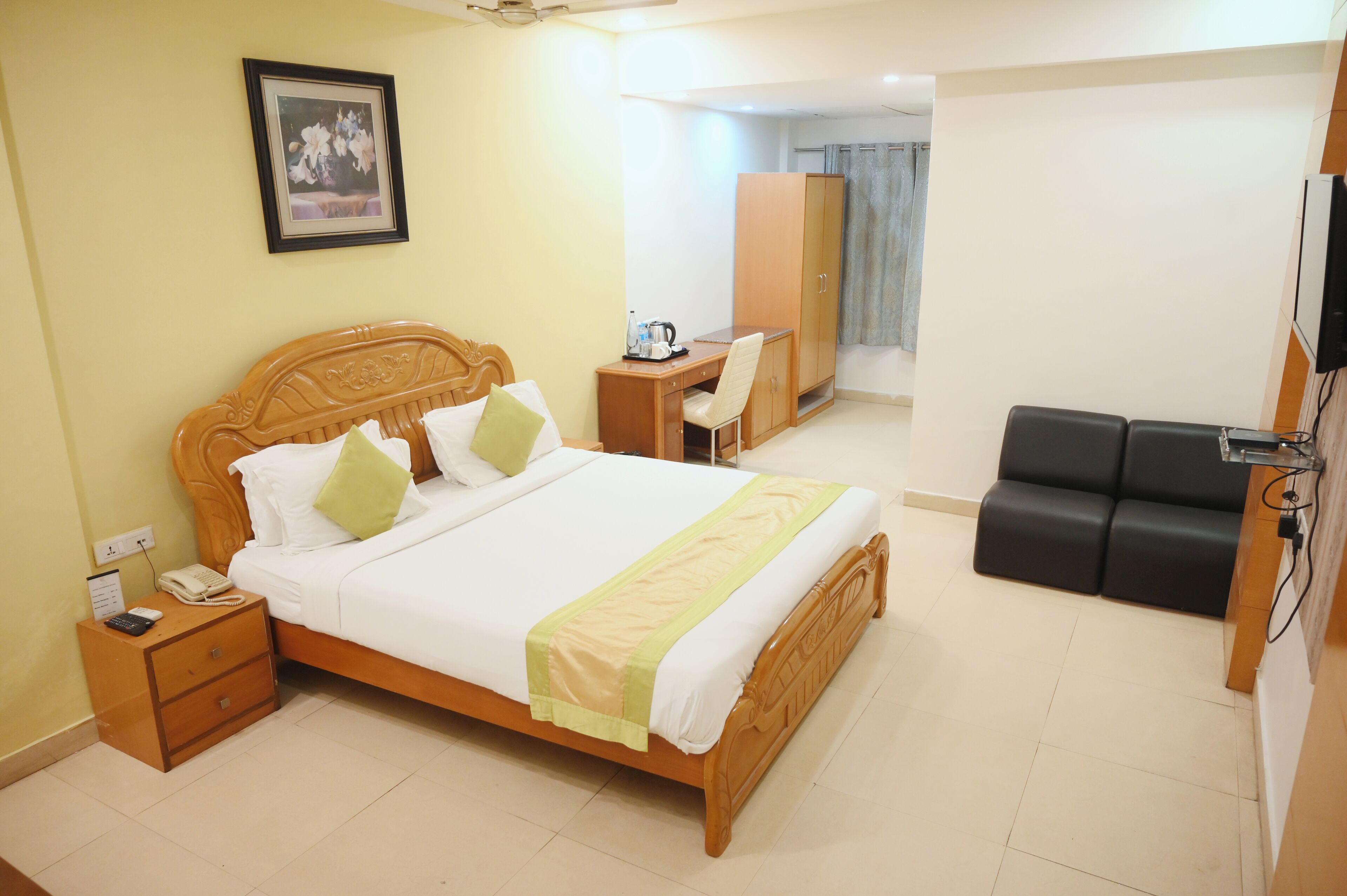 Una habitación de hotel con cama, mesita de noche, escritorio, silla, armario y televisor.
