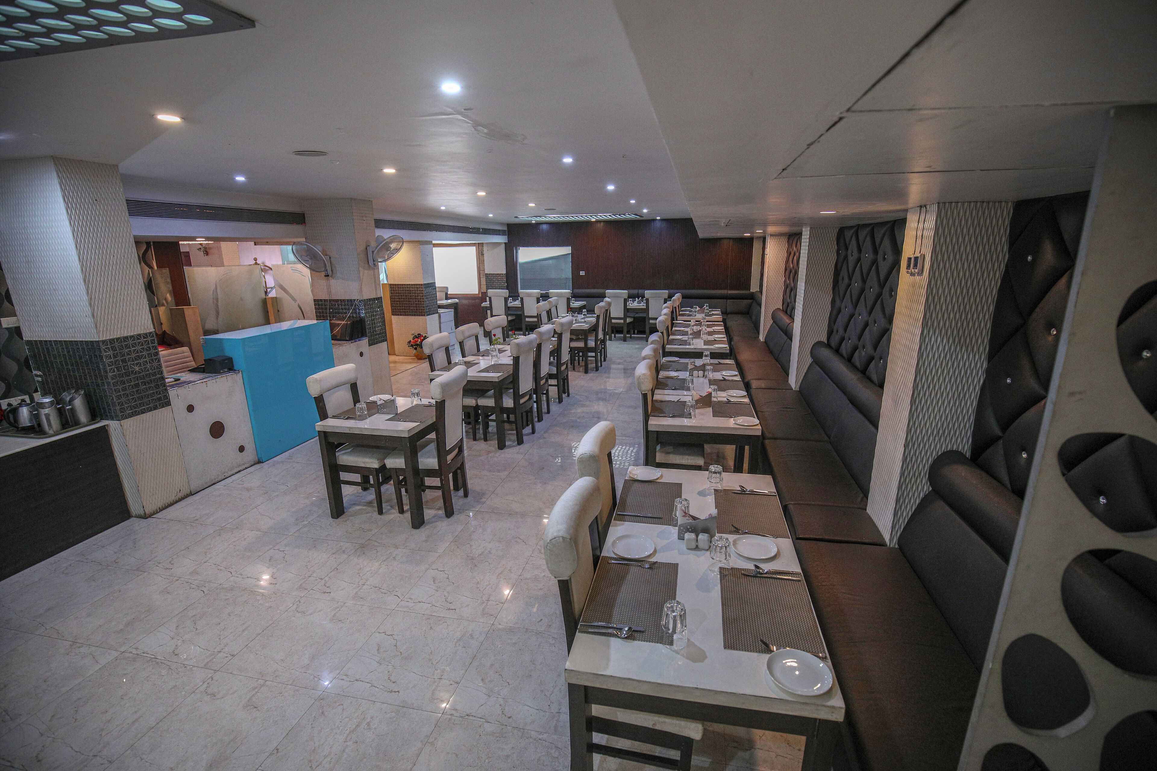 Un restaurante con varias mesas y puestos, una barra y un ventilador grande.