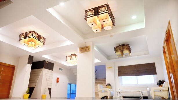 Un vestíbulo de hotel moderno con un diseño limpio y minimalista, que incluye un mostrador de recepción, una zona de estar e iluminación decorativa.