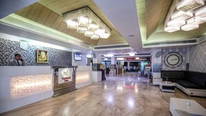 Un vestíbulo de hotel con mostrador de recepción, un reloj y una zona de estar.