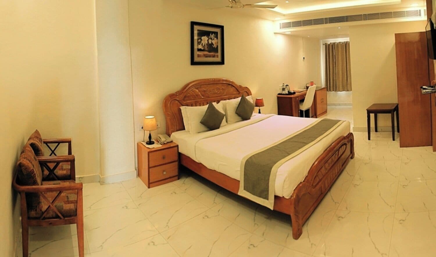 Quarto de hotel com uma cama grande, mesas de cabeceira, uma escrivaninha e uma cadeira.