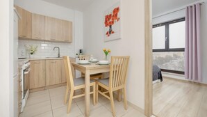 Cozinha moderna com armários de madeira, uma mesa de jantar com cadeiras e uma janela com cortinas.