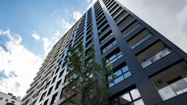 Um edifício moderno de arranha-céu com fachada em forma de grade e várias janelas.